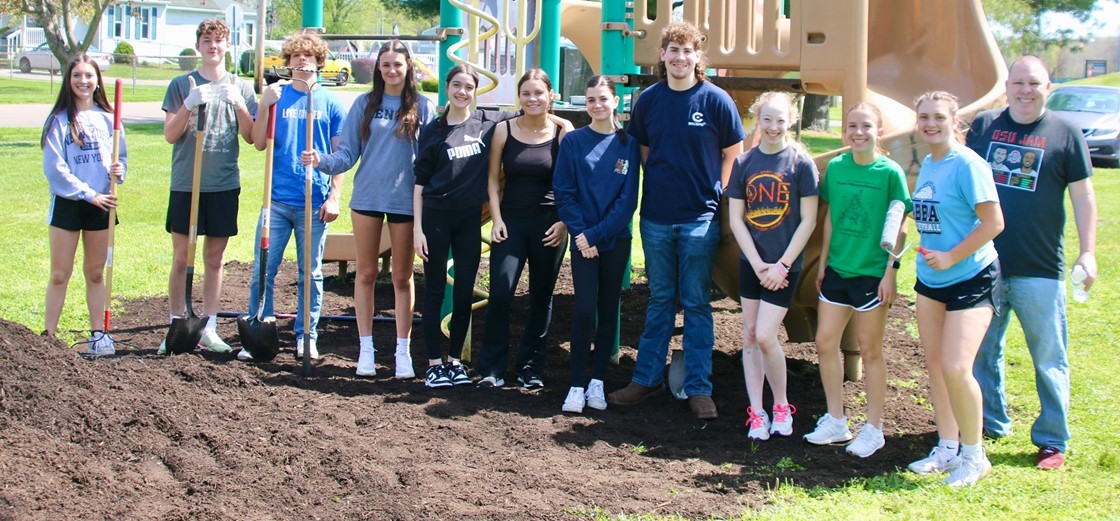 Students posing after spreading mulch at a local playground